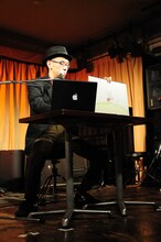 ノートパソコンで音楽を奏でながら演じる河井克夫。