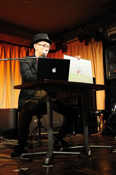 ノートパソコンで音楽を奏でながら演じる河井克夫。