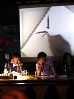 棒状のものを1本書き終えるや、今度は右に50度ほど回転。2本目の棒が逆八の字に配置されたところで、会場に「うわっ、うわっ」「ええええええ」と驚嘆の声が走った。2本の棒は、カイジの眉毛だったのだ。