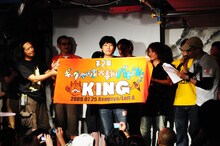 第2回「ギャグ漫画家大喜利バトル」キングの座に輝いたとり・みき。寺田克也より贈呈された勝者の証を掲げる姿は、王者の風格を漂わせている。