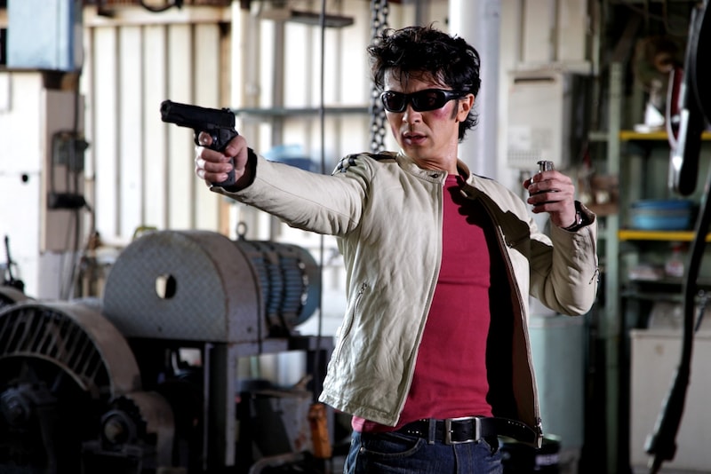 二丁のシンボルである白い革ジャンとサングラスを身につけた武田真治。(c)2009「今日からヒットマン」フィルムパートナーズ