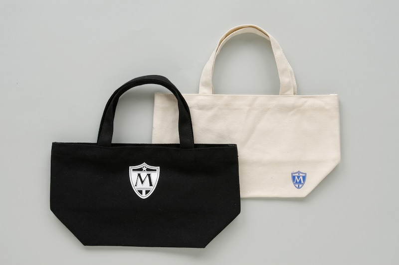 瑞沢高校指定トートバッグ。瑞沢高校の校章が、白は小さめに、黒は大きめにプリントされている。