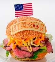 アメリカの「“つまり俺がヒーローだ!!”バーガーセット」は、ナンジャタウン内ノースカントリーキッチンで販売。“HERO”と書かれたチーズをのせたハンバーガー。“O”の文字に描かれているのは宇宙人のトニー。アメリカらしくビッグサイズのハンバーガーだ。たっぷりのローストビーフと、特製ポテトサラダ、オニオンスライス、チェダーチーズ、レタスをサンドし、有精卵で作った特製マヨソースがかけられている 。コーラとポテト付き。