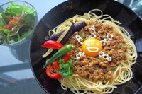 卵黄にオリゼーがマヨネーズで描かれたオリゼー肉味噌納豆パスタ。さらにオクラ、パプリカ、茄子の夏野菜の素揚げをトッピング。サラダ付きで930円。