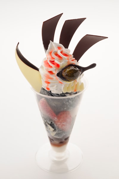 黒装束をイメージした黒ごまアイスの上に、チョコで再現した仮面と斬月を飾り付けた「死神代行黒崎一護卍解パフェ」。 (C)久保帯人／集英社・テレビ東京・dentsu・ぴえろ　(C)劇場版BLEACH製作委員会 2010