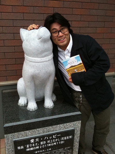 北海道名寄市に設置されたハッピー像と、記念撮影を行う村上たかし。