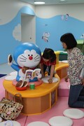 マンガを読むドラえもんと戯れる21世紀の子供たち。(c)Fujiko-Pro