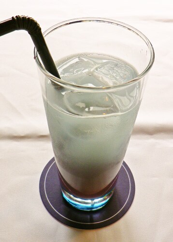 御庭つみきをイメージしたドリンク。ブルーハワイシロップ、プレミアムブルーベリーカルピス、ソーダをミックス。黒ストローで召し上がれ。(C)異識・芳文社／あっちこっち製作委員会