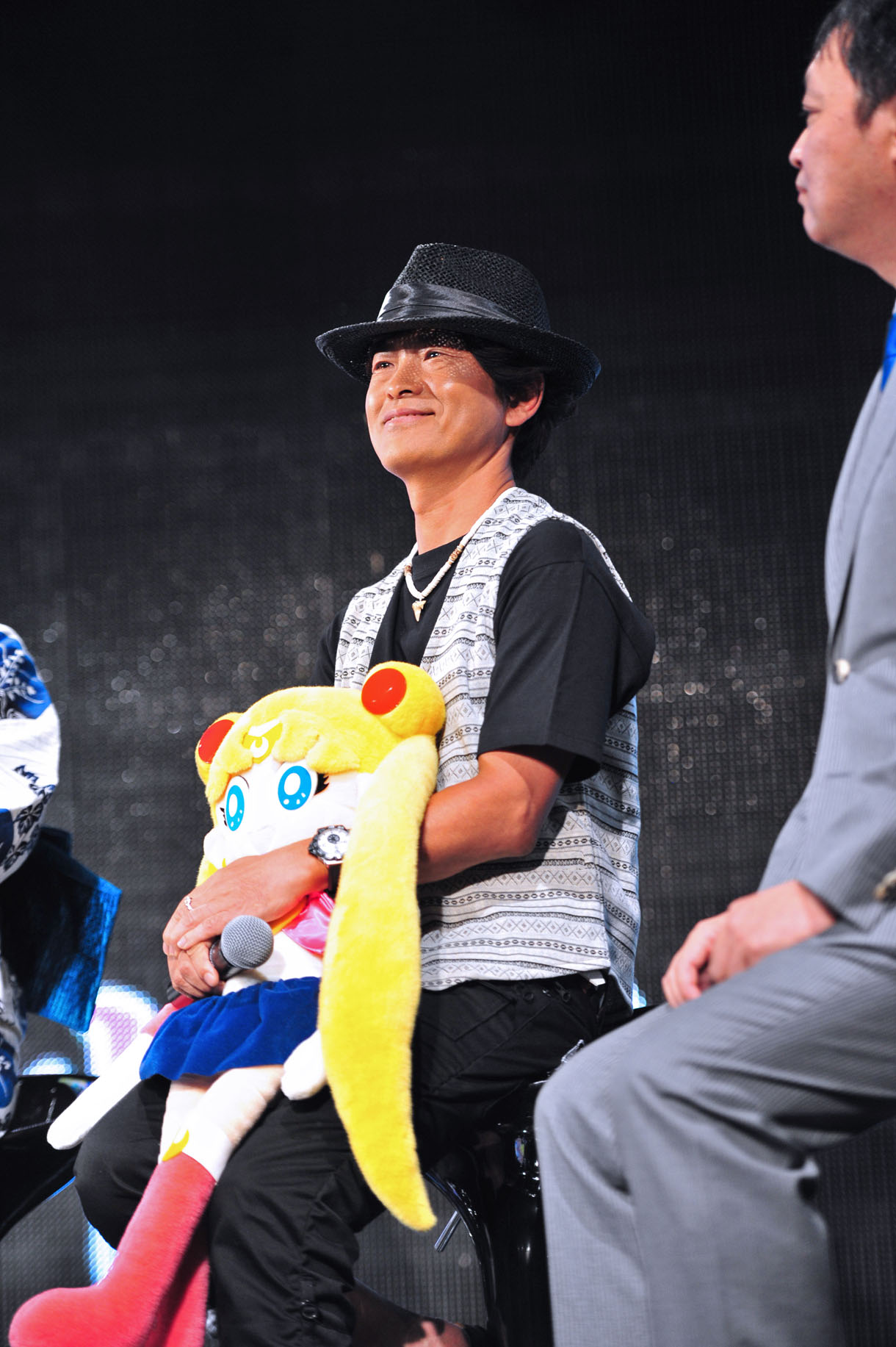 セーラームーンを抱きかかえ、武内が寄せたメッセージに聴き入る古谷。