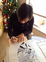 ポスターにサインを入れるカネコアツシ。