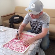 「キン肉マン サイン入り木版画 第20回超人オリンピック RED」にサインを入れる嶋田隆司。