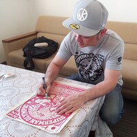 「キン肉マン サイン入り木版画 第20回超人オリンピック RED」にサインを入れる嶋田隆司。