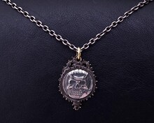 髑髏の騎士のコイン型シルバーペンダント。（c）三浦建太郎(スタジオ我画)/白泉社