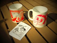 「SUGIURAセット」付属のミニブックと、三角くじで当たるマグカップ。