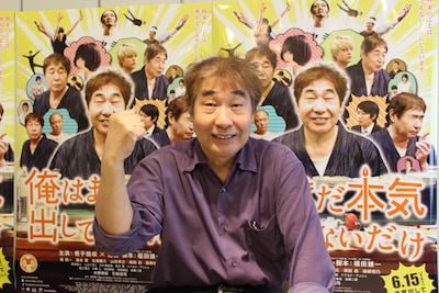 エイプリルフール用に制作された、偽ポスターの前でガッツポーズをする蛭子能収。(C)青野春秋・小学館／「俺はまだ本気出してないだけ」製作委員会　