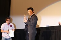 変態仮面フィギュアを手にする鈴木亮平。