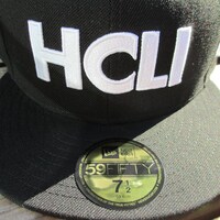 ブラックの「NEW ERAコラボベースボールキャップ」。 (C)2012 高橋慶太郎・小学館／ヨルムンガンド製作委員会