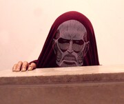 「超大型巨人Tシャツ」をかぶる際は、壁などを使うと効果的だ。(c)諫山創・講談社／「進撃の巨人」製作委員会