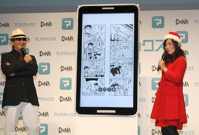 巨人サイズの特大スマートフォンを操作する樹林伸（左）と福田彩乃。