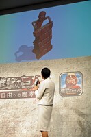 和田アキ子と、期間限定でアプリ内に登場する「アッコ巨人像：食」。