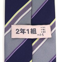 「にゃんぱすネクタイ」のループ部分は、2年1組の室名札になっている。(c)2013 あっと・株式会社KADOKAWA メディアファクトリー刊／旭丘分校管理組合