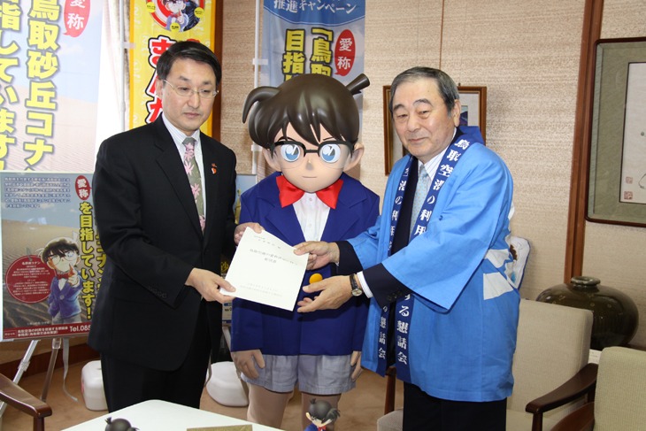 コナンを挟んで平井伸治知事へ要望書を手渡す藤縄匡伸会長。