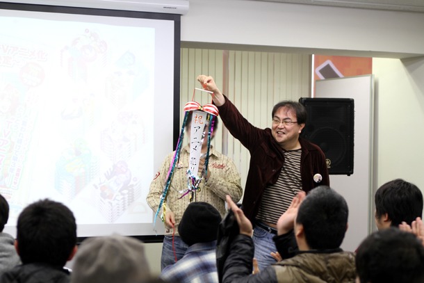 くす玉を持つ猪飼副編集長と、紐を引っ張るオカヤド。アニメ化をお祝いし、会場には拍手が鳴り響いた。