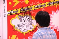 コロコロコミックを模した巨大モニュメントにサインをする松本しげのぶ。