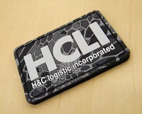 「ヨルムンガンド」の「HCLI PVCパッチ」。コミックマーケット89では「HCLI M-65ジャケット」とのセットでの取り扱いとなる。