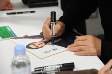 色紙にサインをする池上遼一。