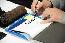 単行本にサインをする山本英夫。