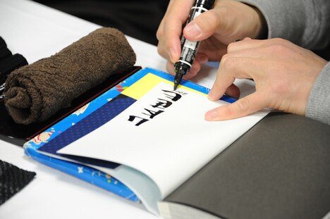 単行本にサインをする山本英夫。