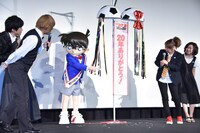 垂れ幕に何かが書いてあることを、キャスト陣に教えるコナン。