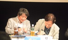 色紙にサインを入れる石川サブロウと、村上もとか。