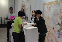 観客にサイン入りの図録を手渡す坂本眞一。