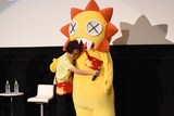 「うどんの国の金色毛鞠」先行上映会の様子。ガオガオちゃんの着ぐるみと抱き合う宅野誠起監督。