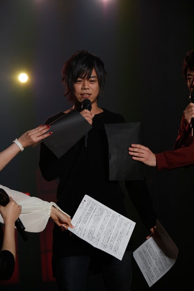 色黒であることをイジられた浪川大輔は、舞台裏を全身黒の衣装で歩いていた際に「鳥海（浩輔）さんに『服着ろよ』って言われた」と明かす。写真はそんな浪川に「隠してください」と台本を被せるキャスト陣の様子。