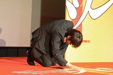 壇上の映画ロゴに触れる綾野剛。