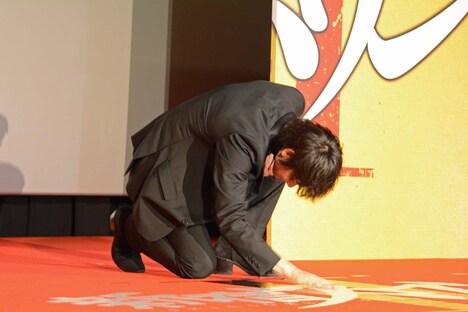 壇上の映画ロゴに触れる綾野剛。