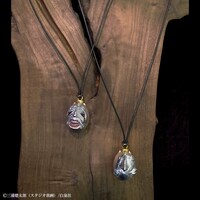 「ベヘリット2017 蝕 メタルコーティング版ペンダント ART OF WAR創業20周年特別版」（左）と「ベヘリット2017 覇王の卵 メタルコーティング版ペンダント ART OF WAR創業20周年特別版」（右）。