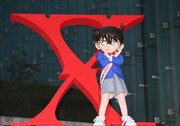 紅に染まった「Xロゴ」の前で、Xポーズを披露する江戸川コナン。