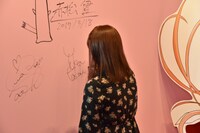 高倉有加が壁面にサインしている様子。