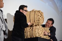 米俵を持ち上げる吹越満。