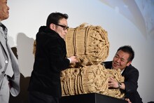 米俵を持ち上げる吹越満。