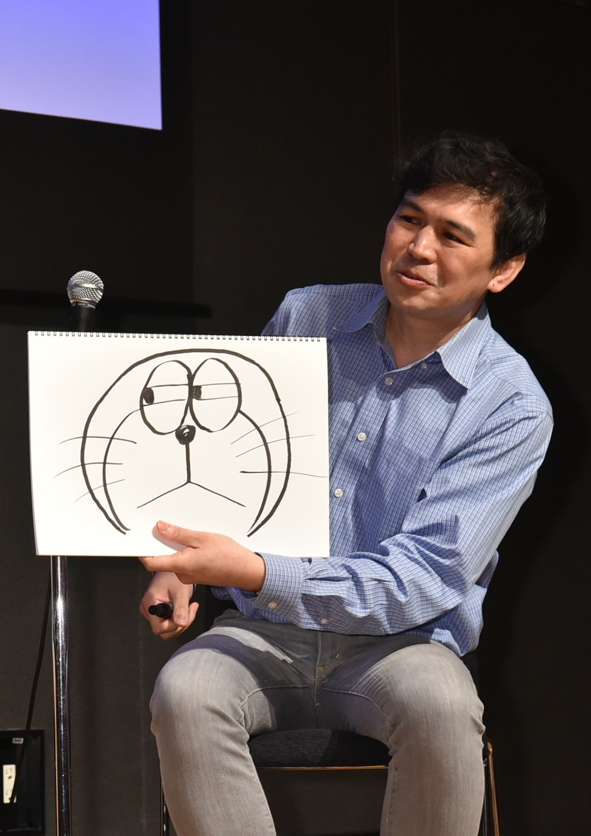 「この表情が好きなんです」と話しながら、描いたドラえもんを見せる西尾康之。