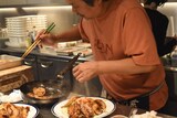 豚の生姜焼きを盛り付けるきくち正太。お皿も家から持参したというこだわりのもの。