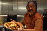 豚の生姜焼きを持ったきくち正太。