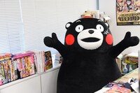 中野博之編集長のデスクに座り編集長気分を味わうくまモン。