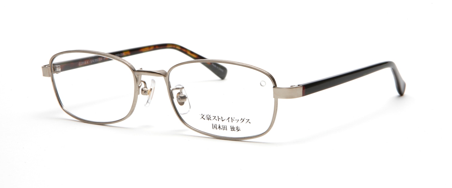 国木田独歩モデルのフロントは、国木田のクールさをイメージしたシルバーのメタルを採用し、縁にはレトロな彫金を施す。ツルの内側は深いデミブラウン。外側は一見黒く見えるが、光にかざすと国木田が愛用している理想手帳をイメージしたモスグリーンになる。蝶番とツルの付け根には国木田のリボンのエンジ色を入れている。