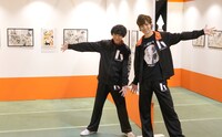 原画展会場を回る須賀健太と影山達也。